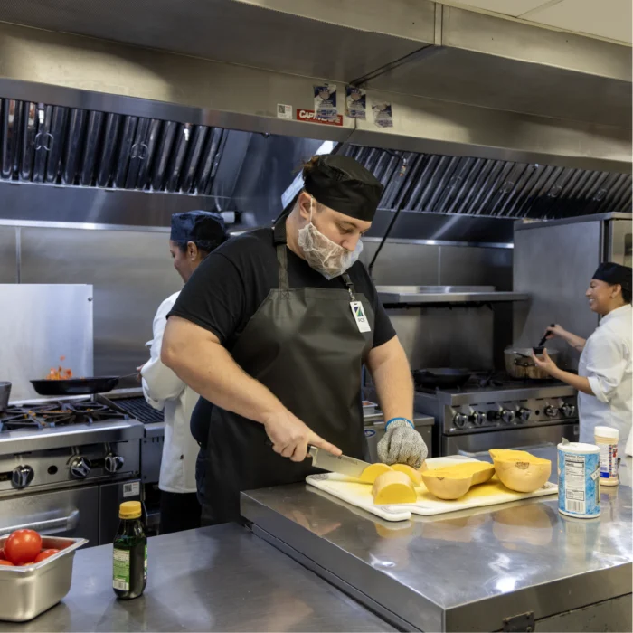 male employee working and cutting fruit in a kitchen