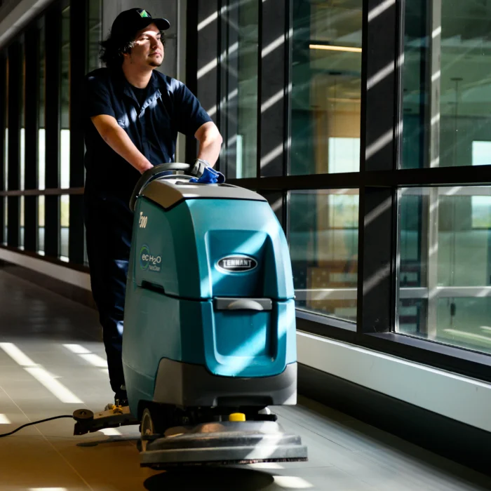 male employee sweeps floors with machine and has a limb difference