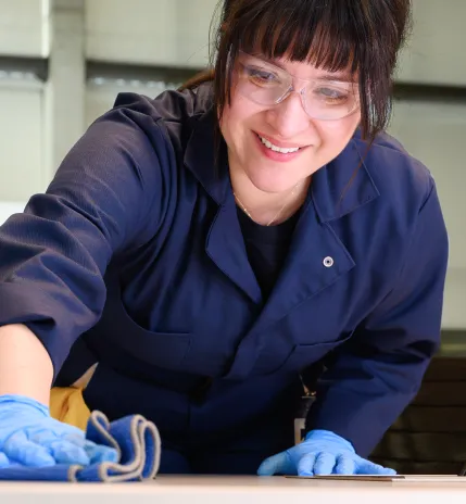 A young female PCSI employee wearing protective eye wear cleans a table.