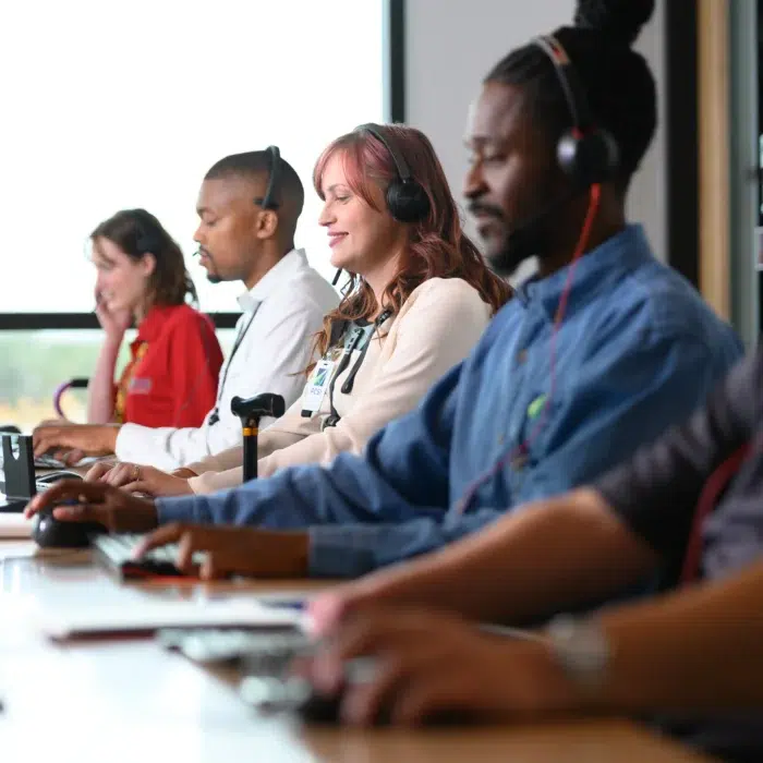 men and women working next to each other in a telecommunications setting